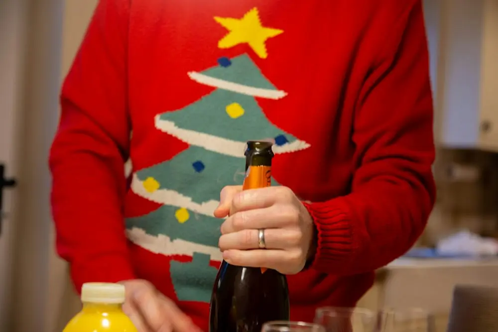 A person in a red sweater with a decorated Christmas tree on the front